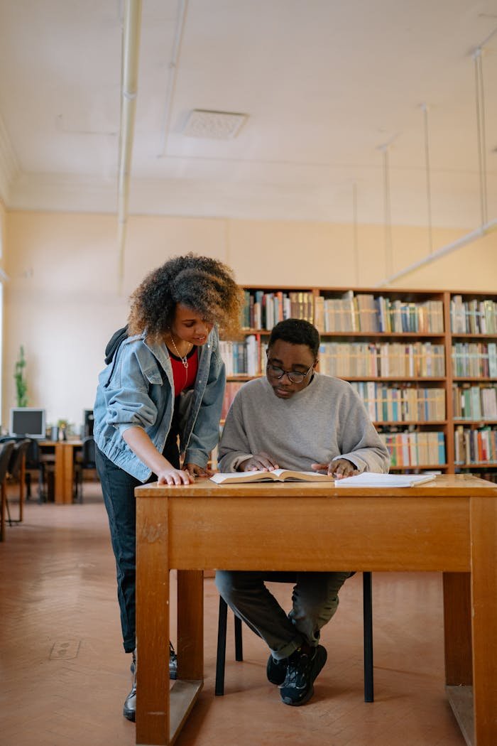 why-choose-us Two university students studying together in a library, focusing on textbooks and learning.