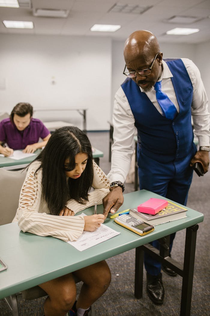 team-01 Educator assisting student during an exam in a classroom setting, emphasizing support in education.